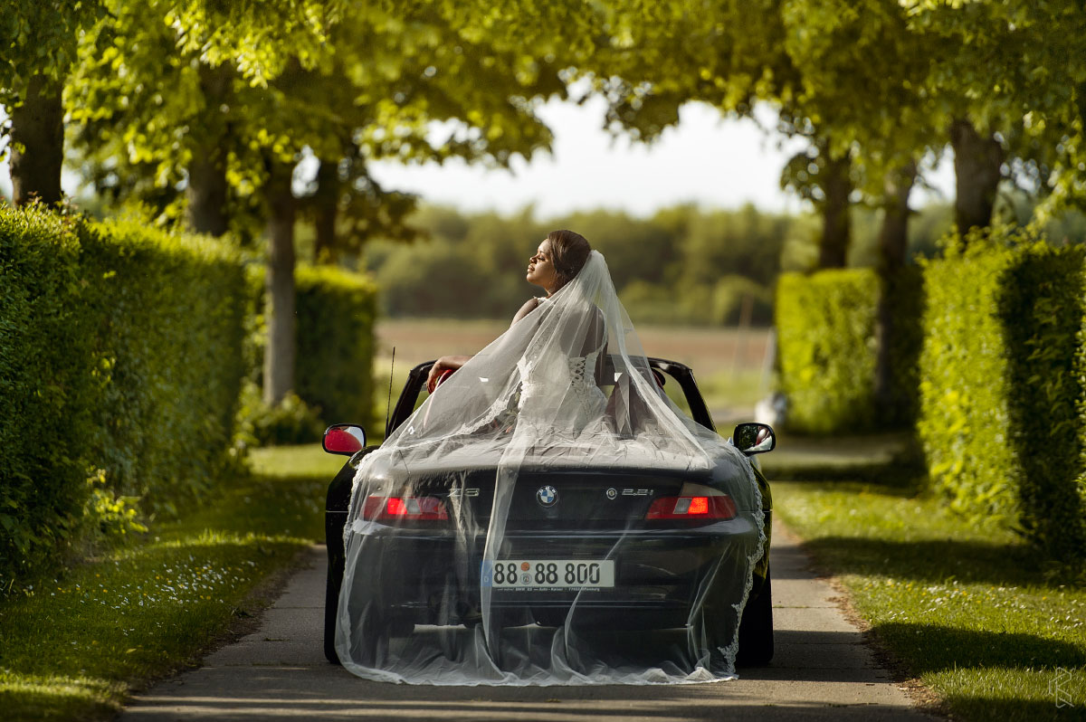 Brautfoto in einem BMW Z3 von Hochzeitsfotograf Frankfurt, der Braut hat ein sehr langes Schleier