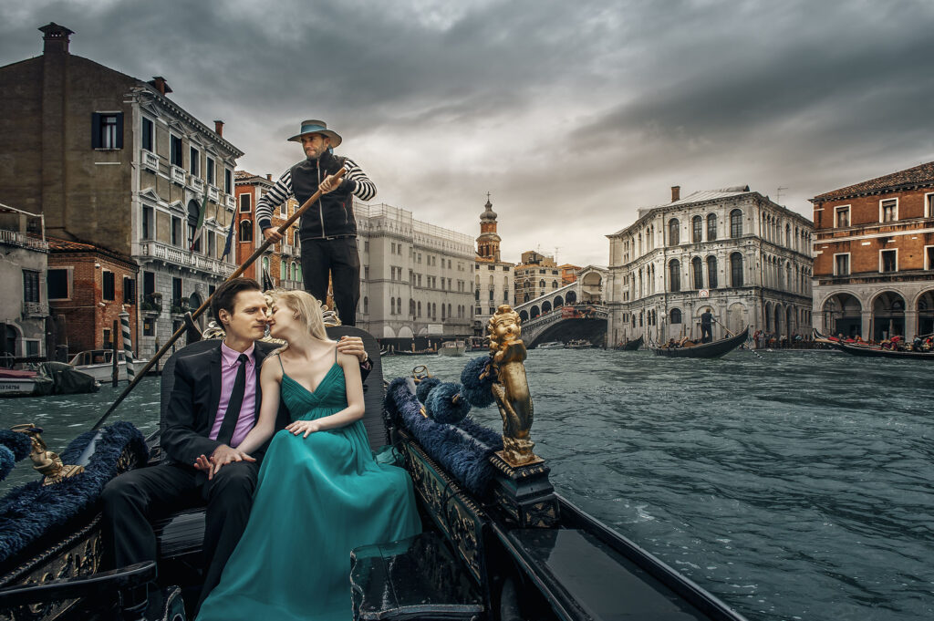 Dreamy blue-hour pre-wedding in Venice – Chinese couple sharing a passionate embrace on a classic gondola, bride radiant in elegant long blue dress, with the majestic Rialto Bridge glowing softly behind them in the heart of the canal city.